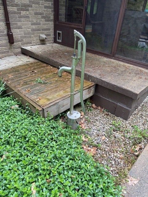 A water pump is sitting next to a wooden deck.