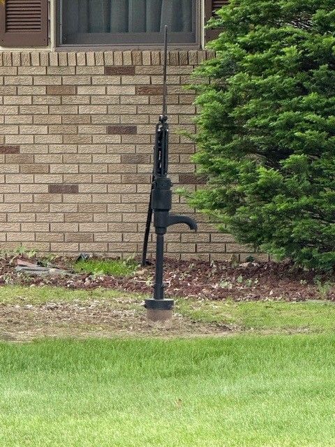 A brick building with a water pump in front of it
