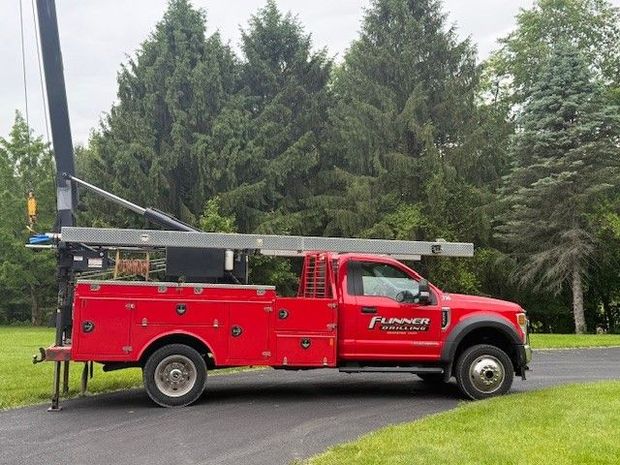 A red truck with a crane on top of it is parked on the side of the road.