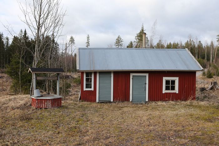 A red shed with a well in front of it