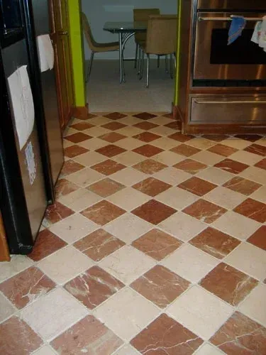 Diamond-patterned red and cream-colored floor in a kitchen, with a refrigerator and oven visible.