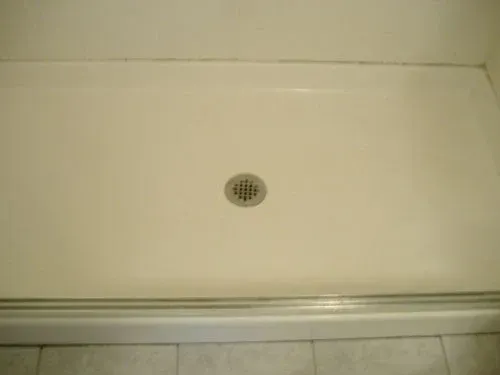 A white shower base with a central drain.