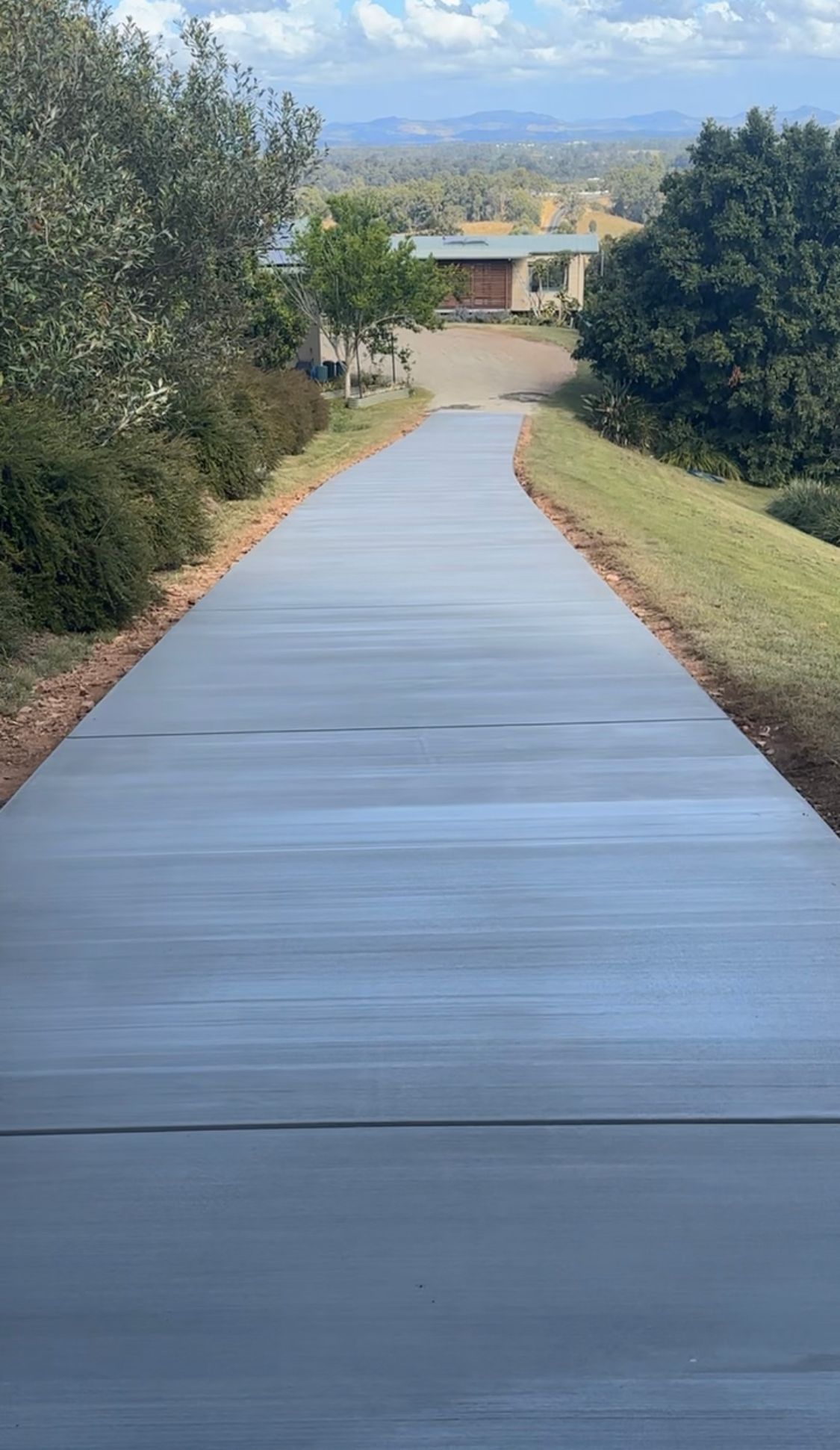 A Concrete Driveway Leading to a House With Trees on Both Sides — Peter Bishop Concreting In Gympie, QLD