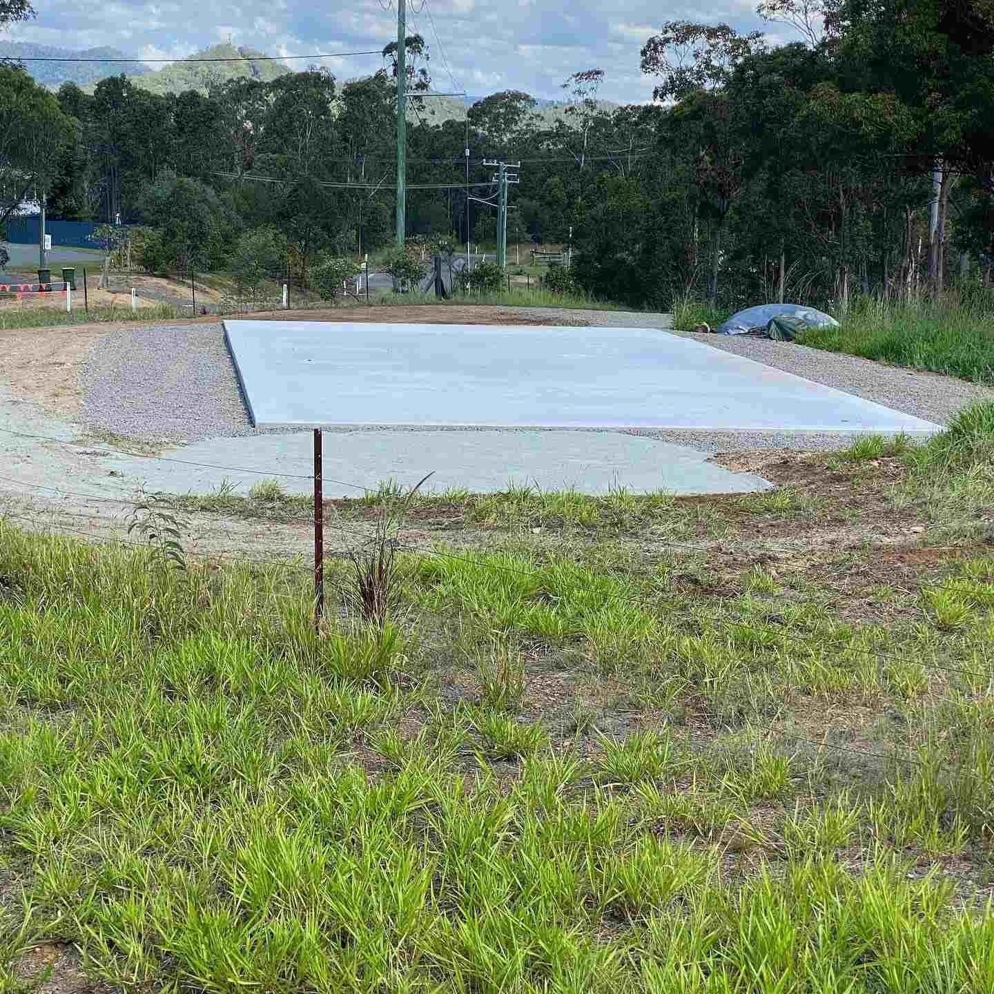 A Large Concrete Slab is Sitting in the Middle of a Grassy Field — Peter Bishop Concreting In Cooroy, QLD
