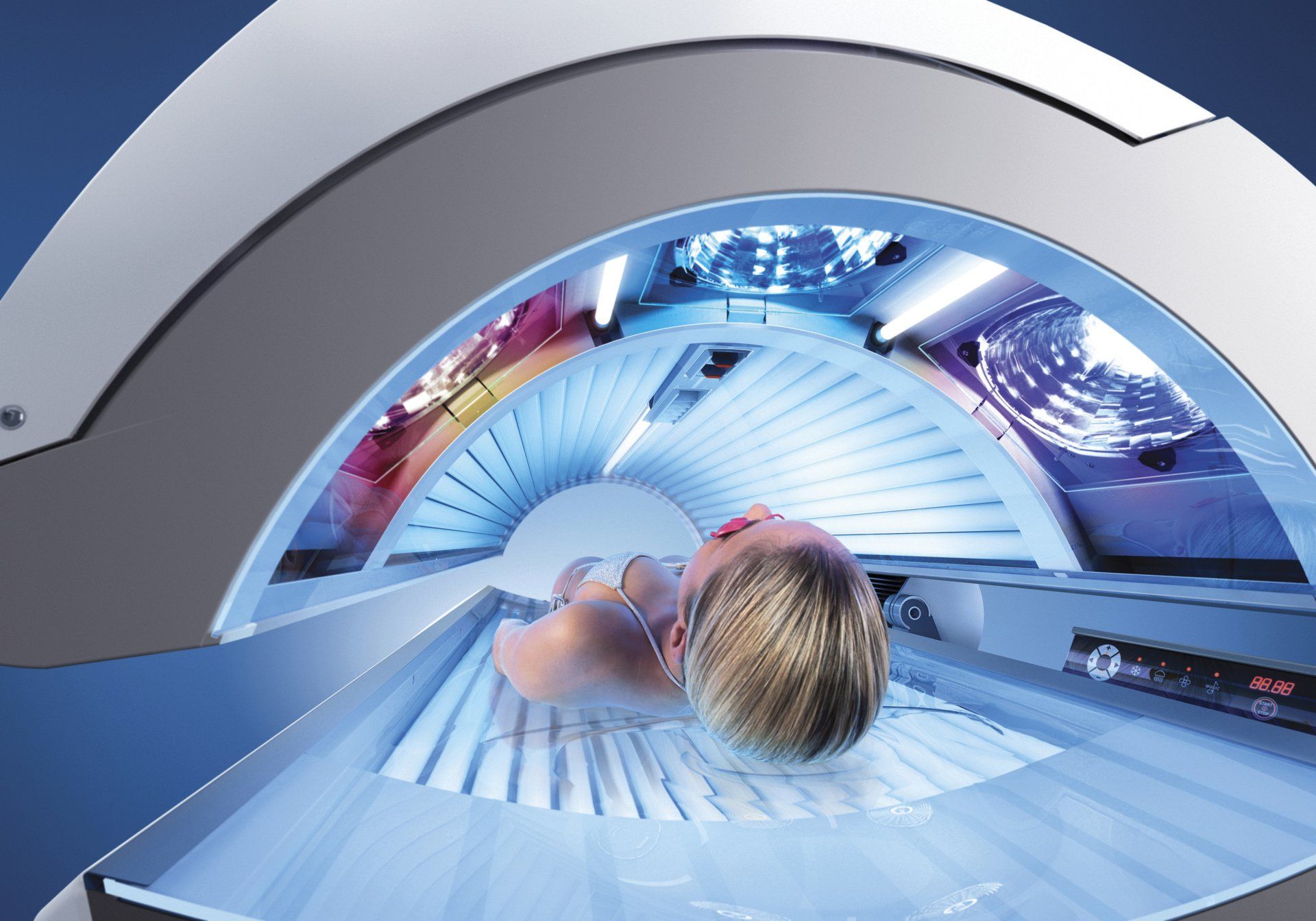 A woman is laying in a tanning bed with the lights on