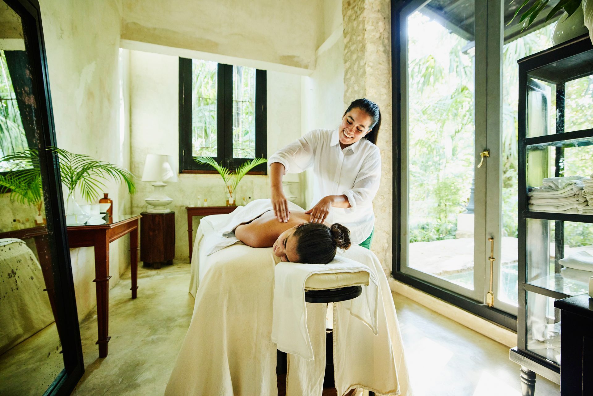 Woman receives relaxing back massage in a serene room offering spa services.