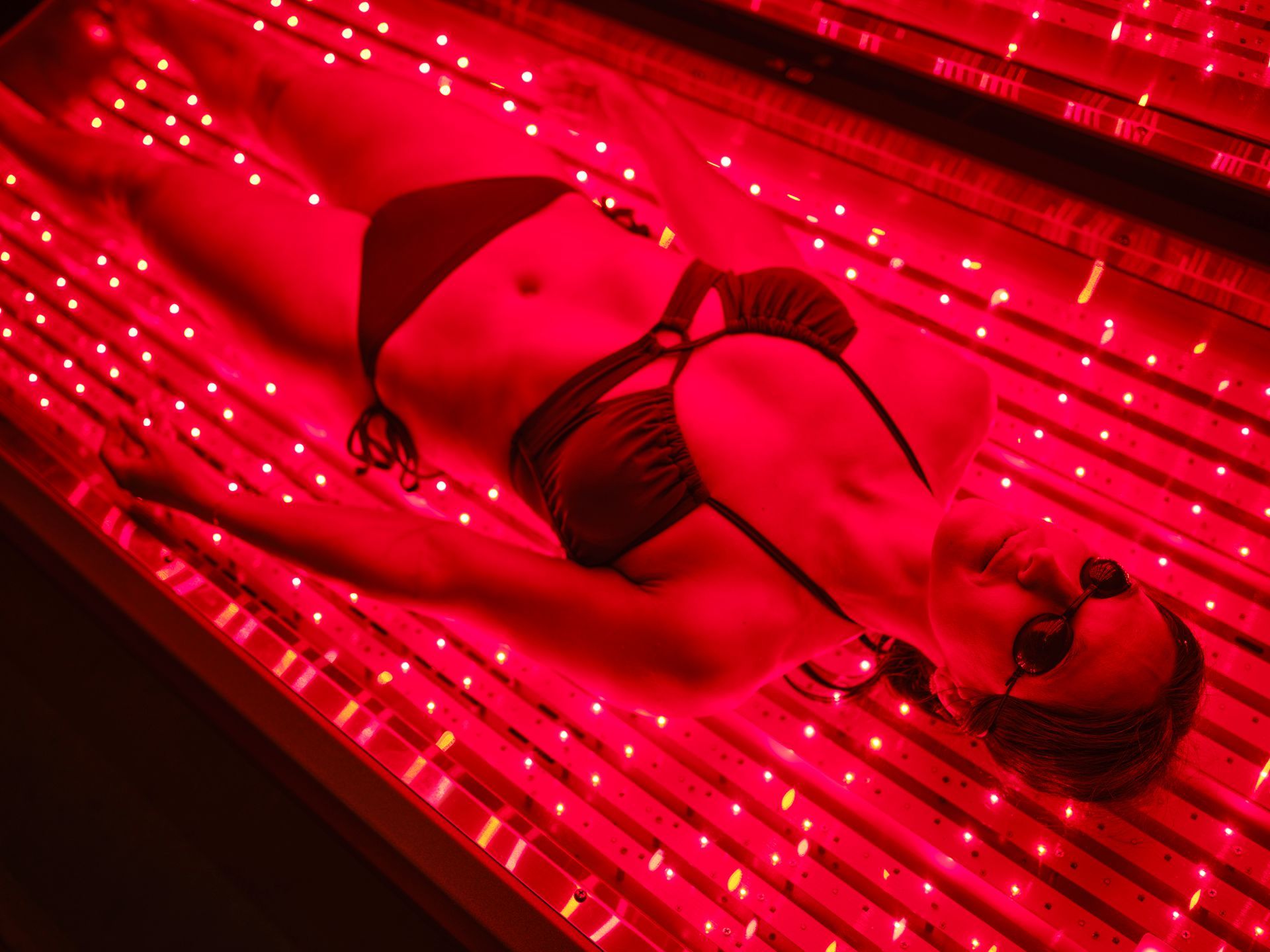 A woman on an LED light bed, receiving red light therapy. A woman on an LED light bed, receiving red light therapy.