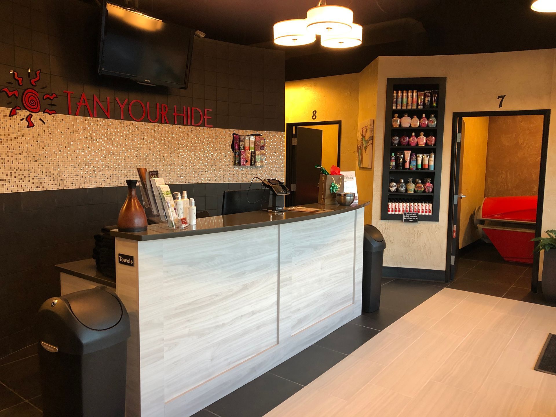 A reception desk in a tanning salon with a tv on the wall.