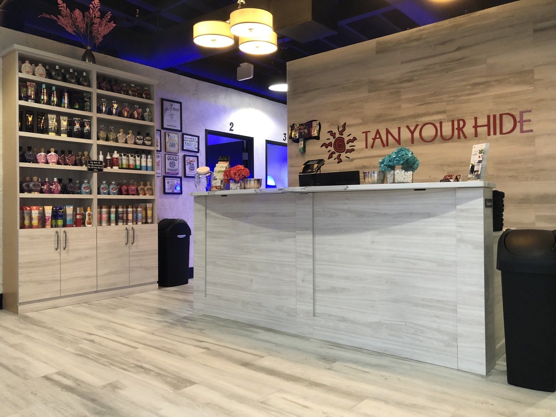 A tan your hide salon with a reception desk and shelves filled with bottles of tanning products.