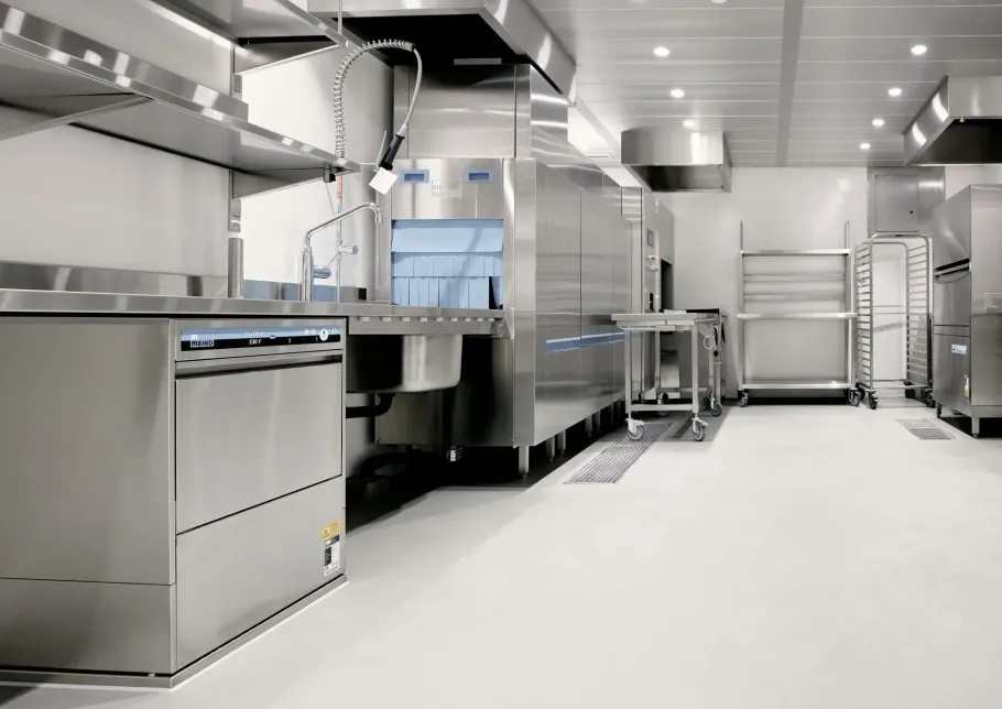 Clean commercial kitchen with stainless steel appliances and bright white floors