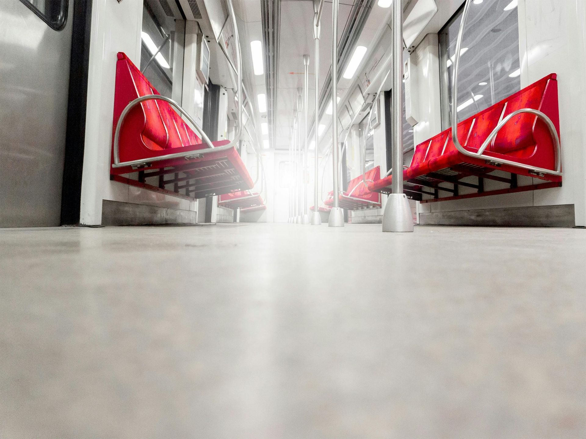 Modern transit station with red benches and bright lights, viewed from a low floor-level angle