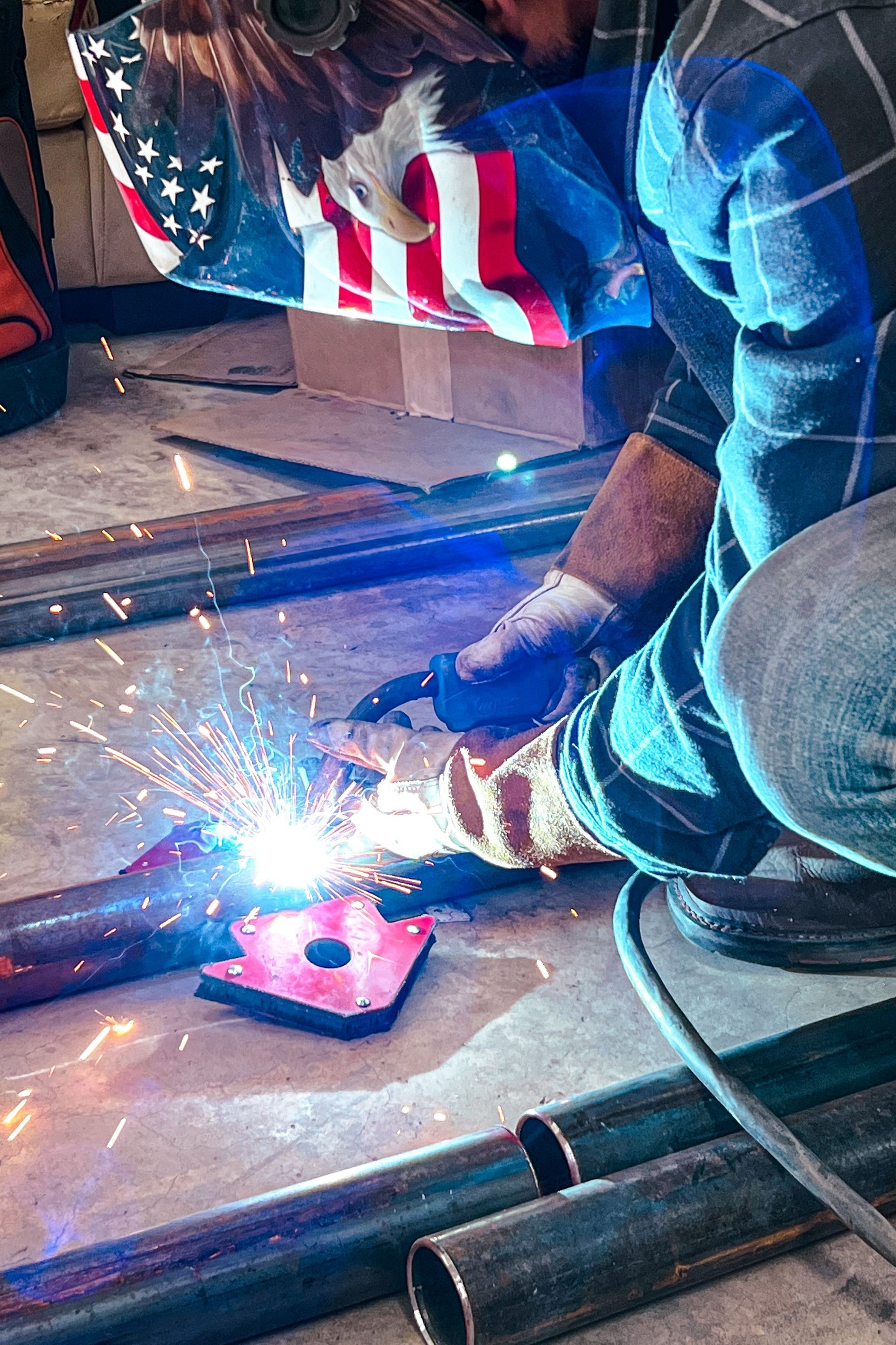 A man wearing an american flag helmet is welding a fence