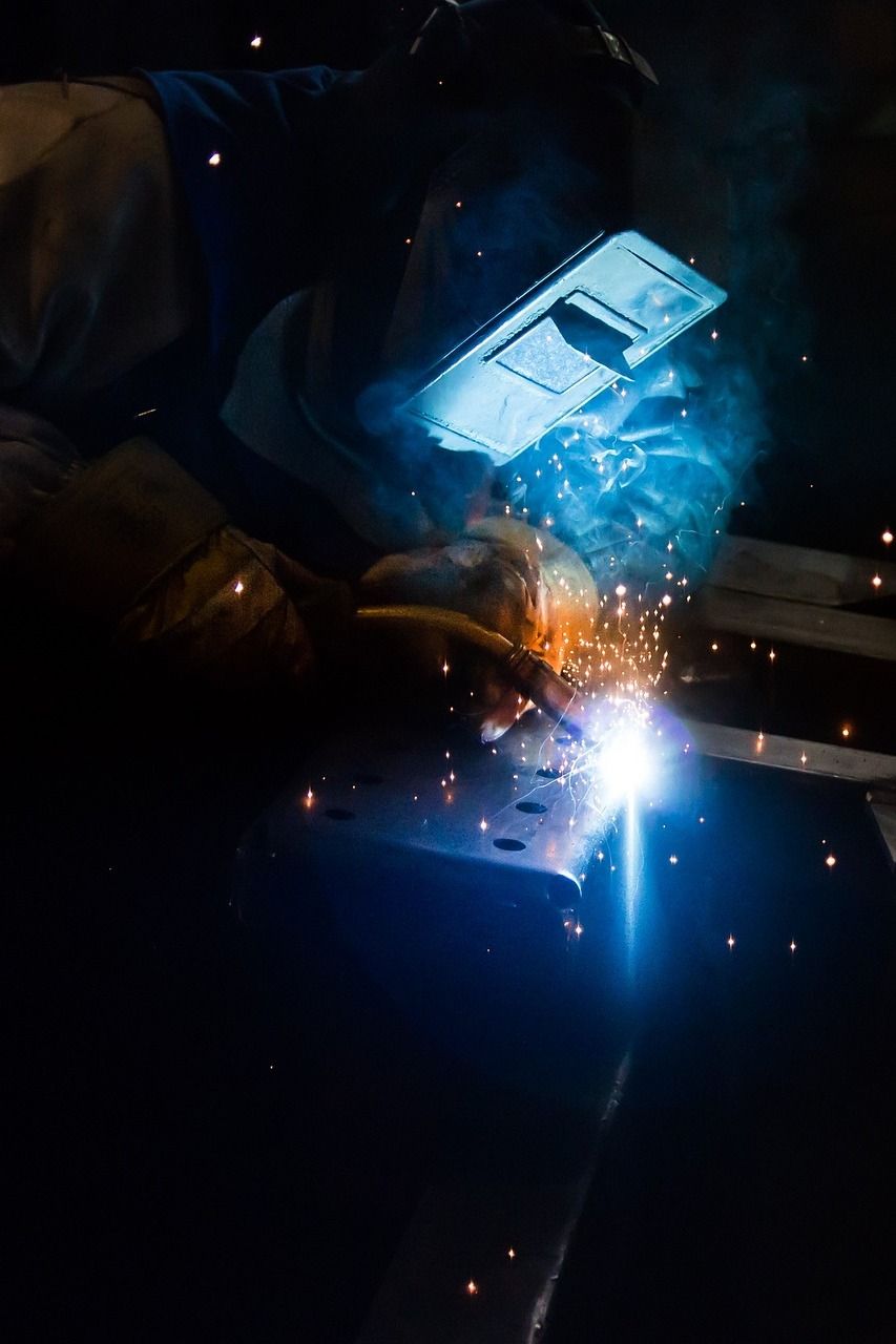 A man is welding a piece of metal in a dark room.
