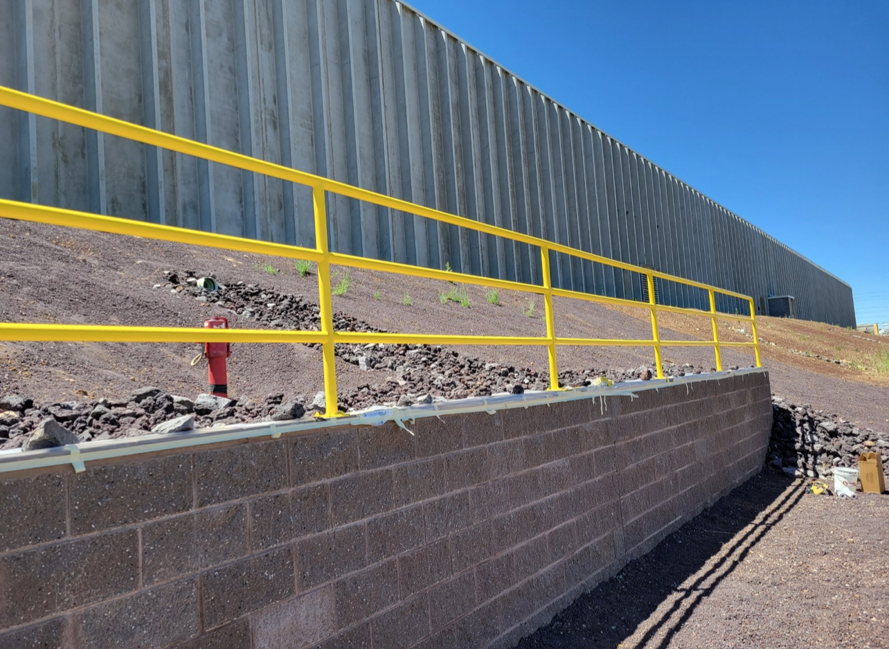 A yellow railing on a brick wall next to a building.