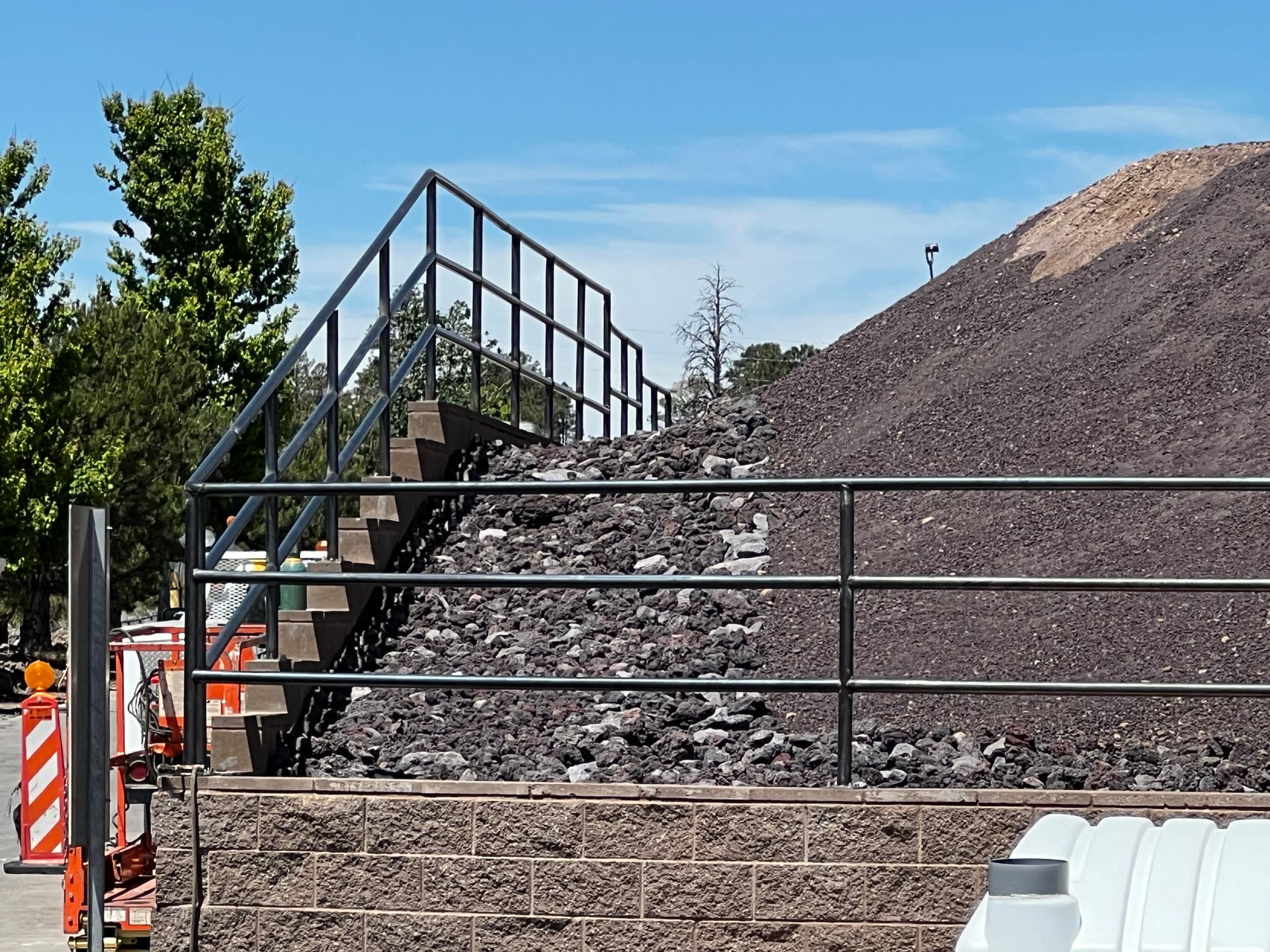 A large pile of rocks is behind a metal fence