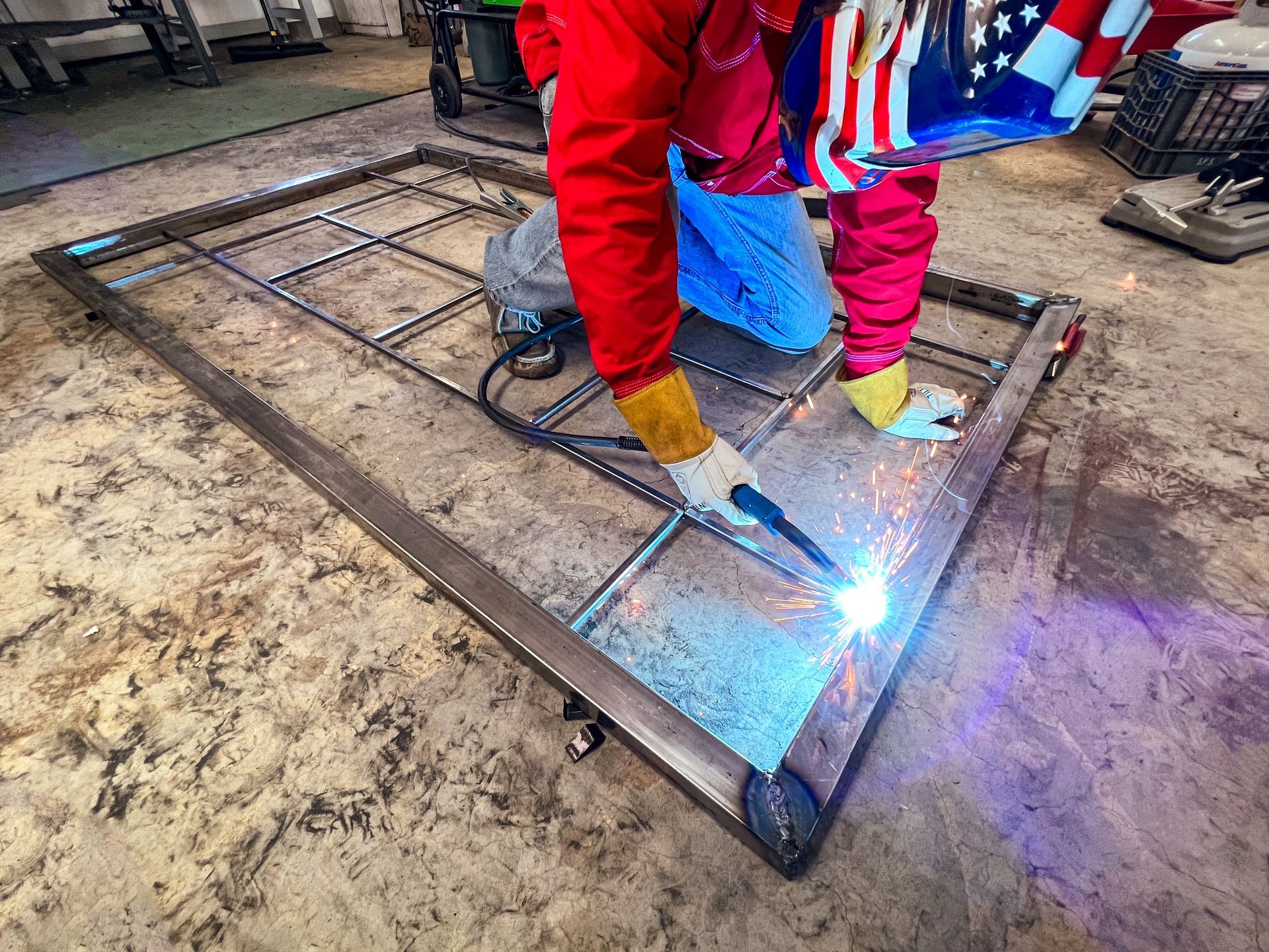 A person is welding a piece of metal in a factory.