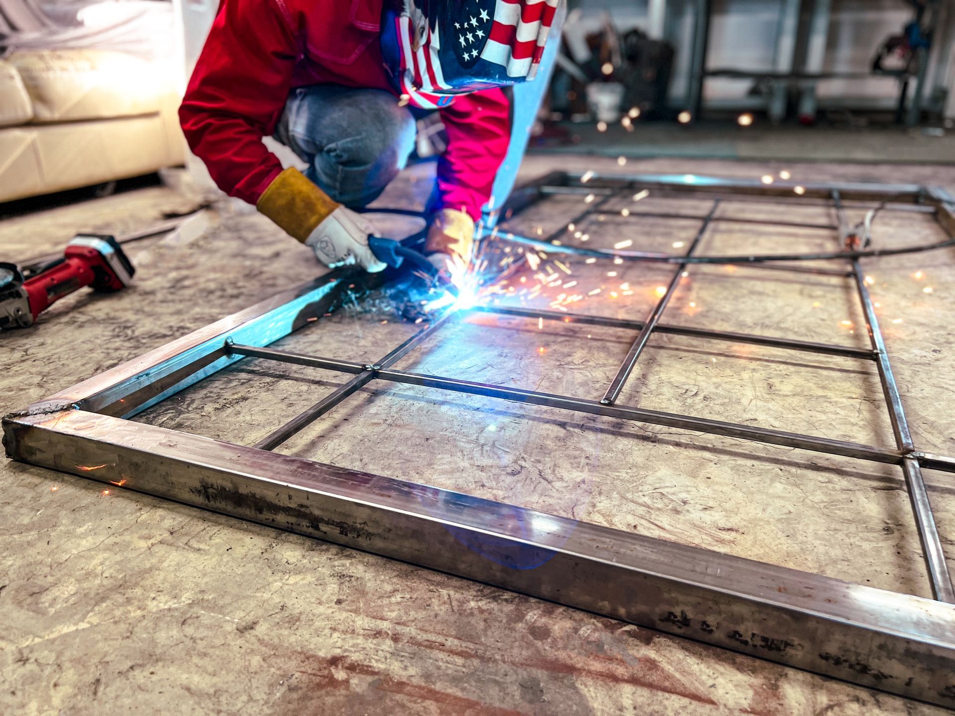 A man is welding a piece of metal on the floor.