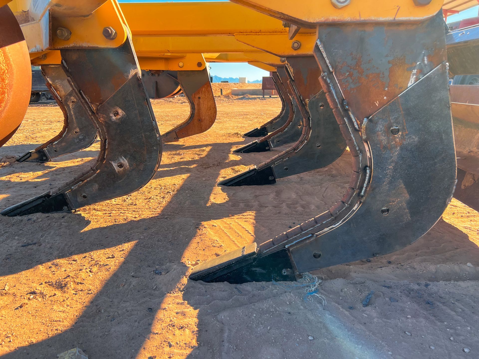 A row of tractors are lined up in the dirt.