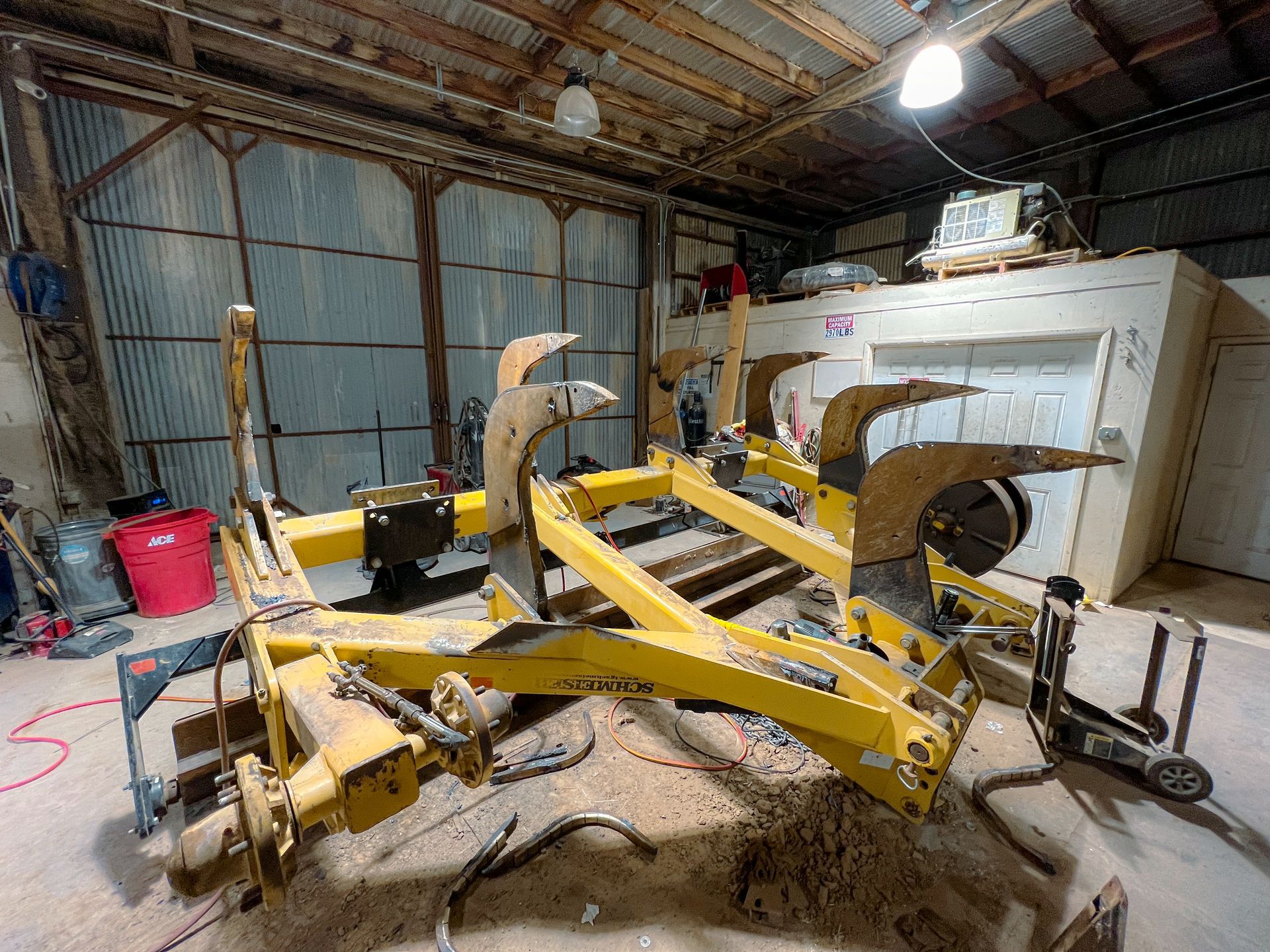 A yellow plow is sitting in a garage.