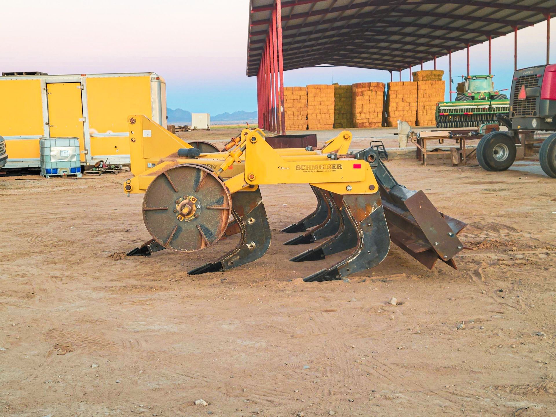 A yellow tractor is parked in a dirt field