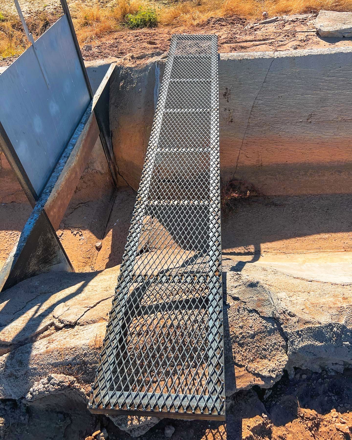A metal ladder is sitting on top of a rock.