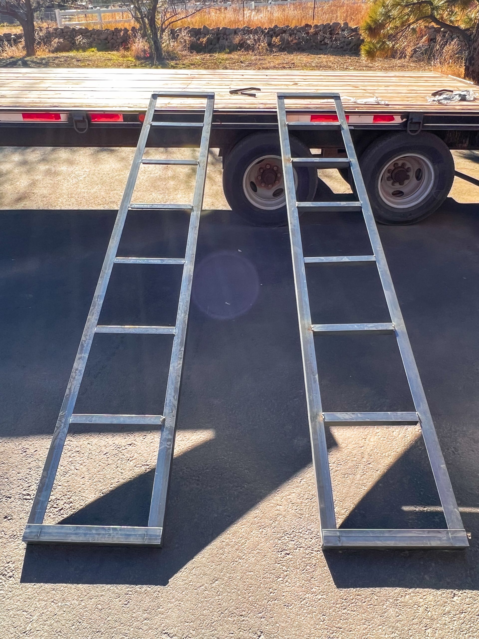 A pair of metal ramps are sitting in front of a trailer