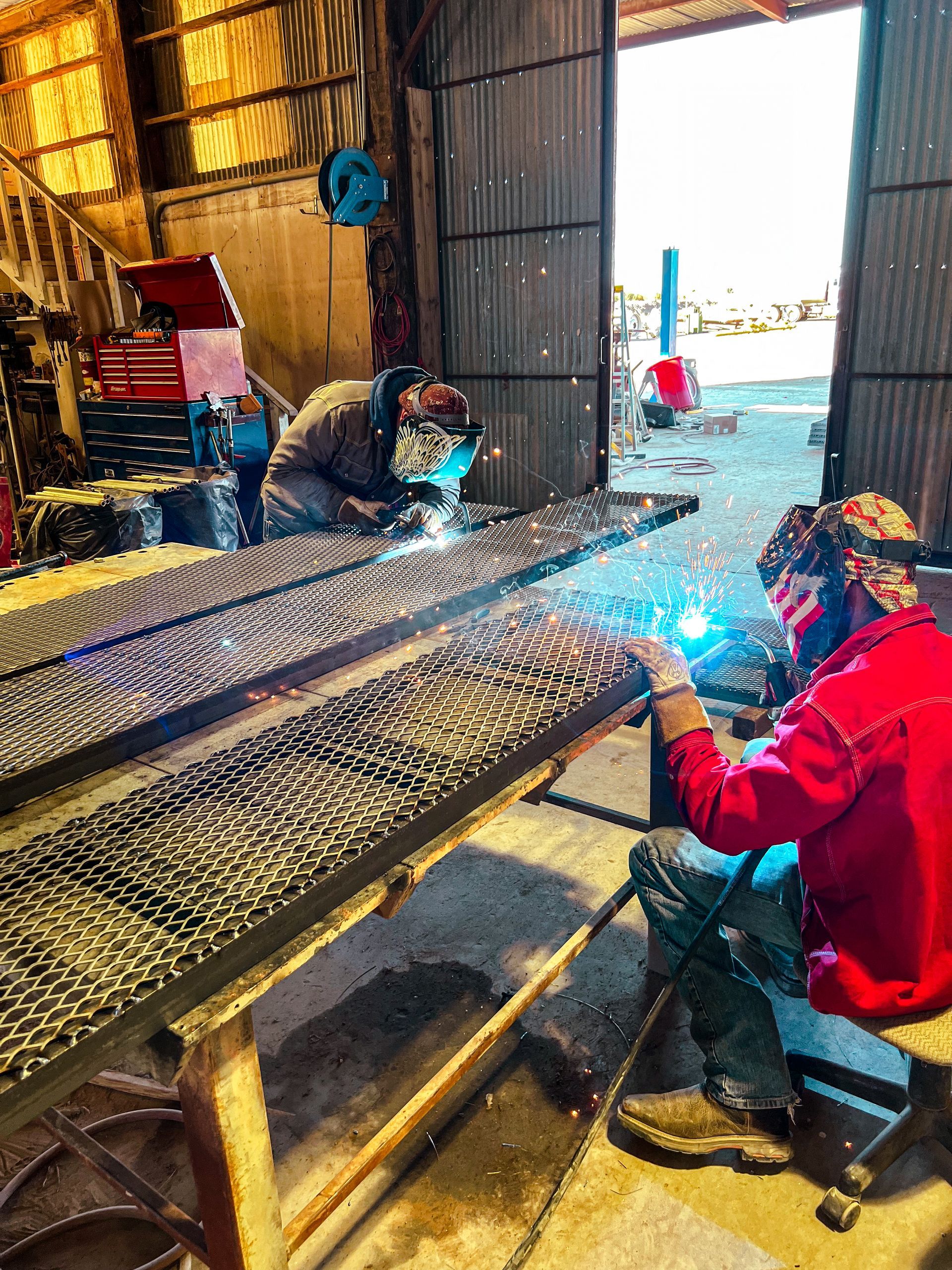 A man is welding a piece of metal in a factory.