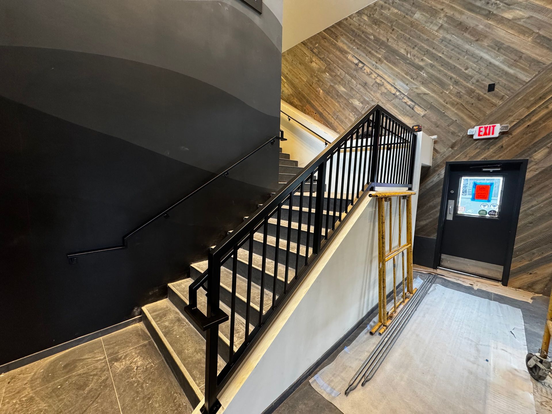 A yellow railing on a brick wall with a pile of rocks in the background