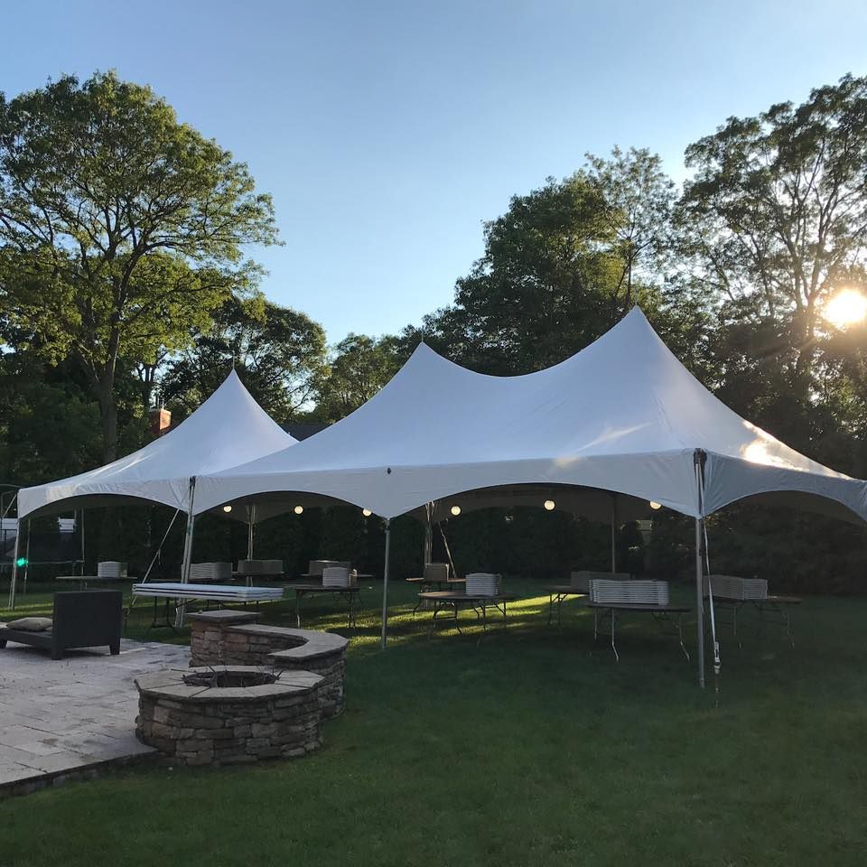 A large white tent is sitting in the middle of a lush green field.