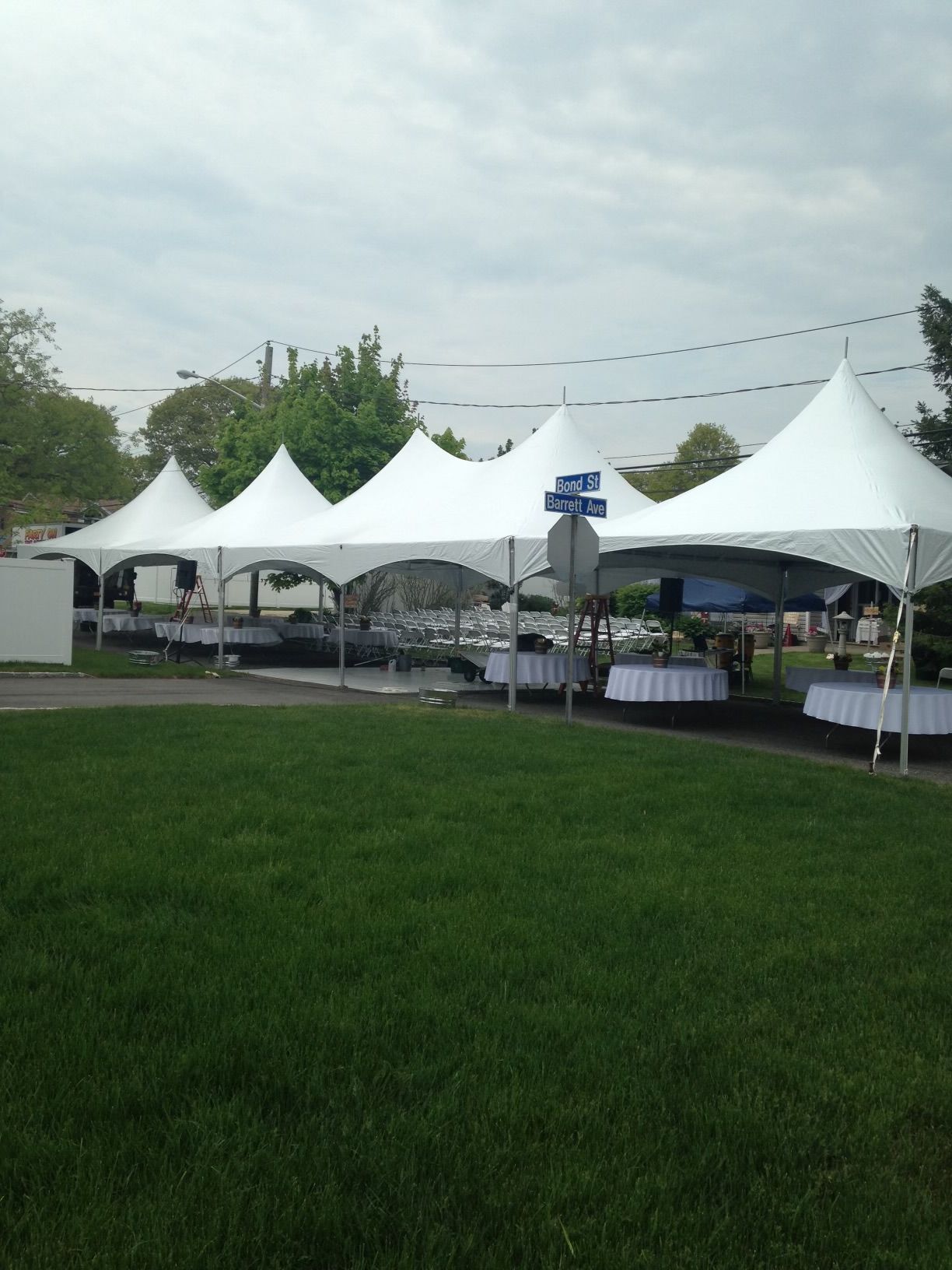 A row of white tents are set up in a grassy field