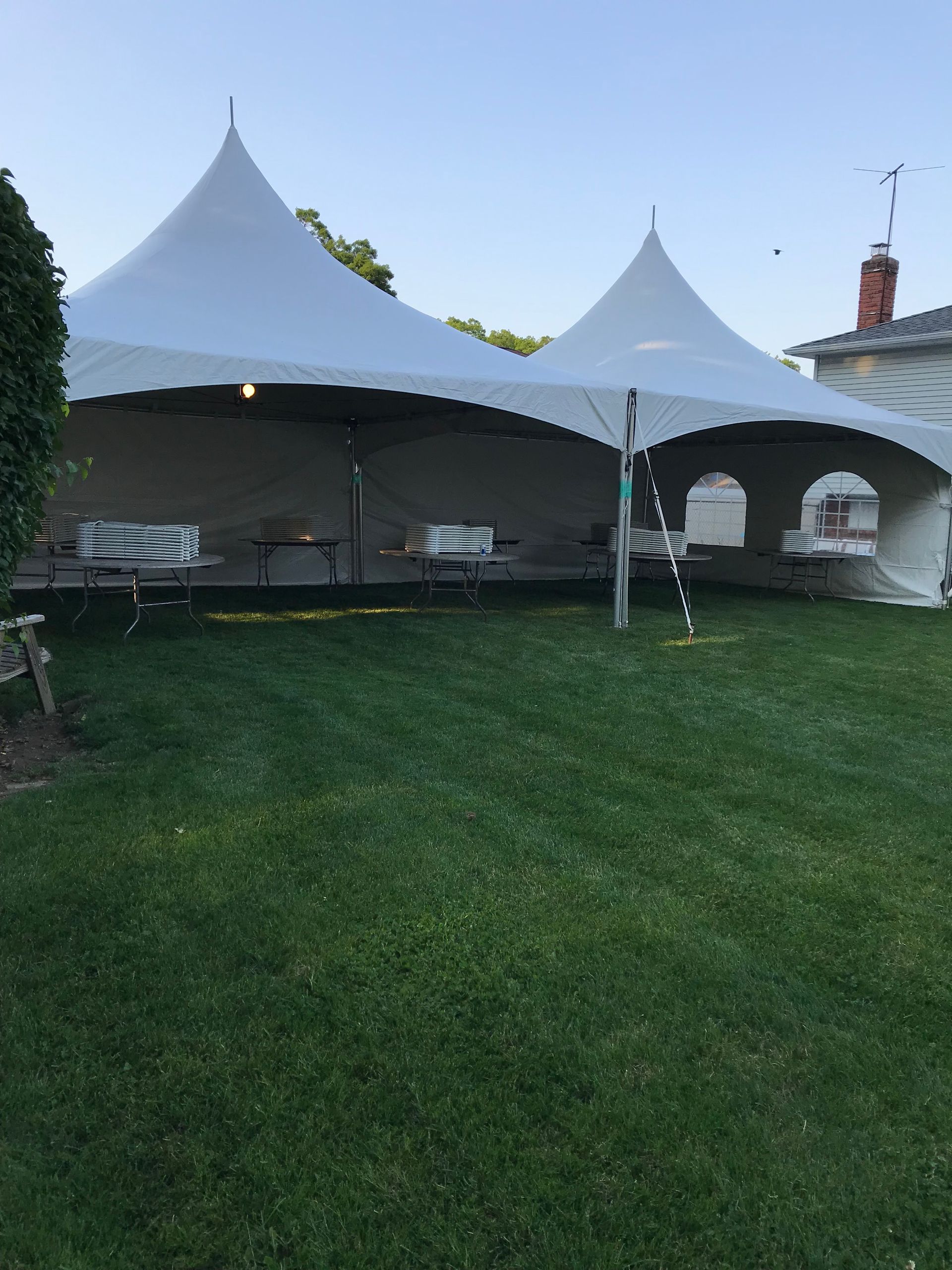 Two white tents are sitting on top of a lush green field.
