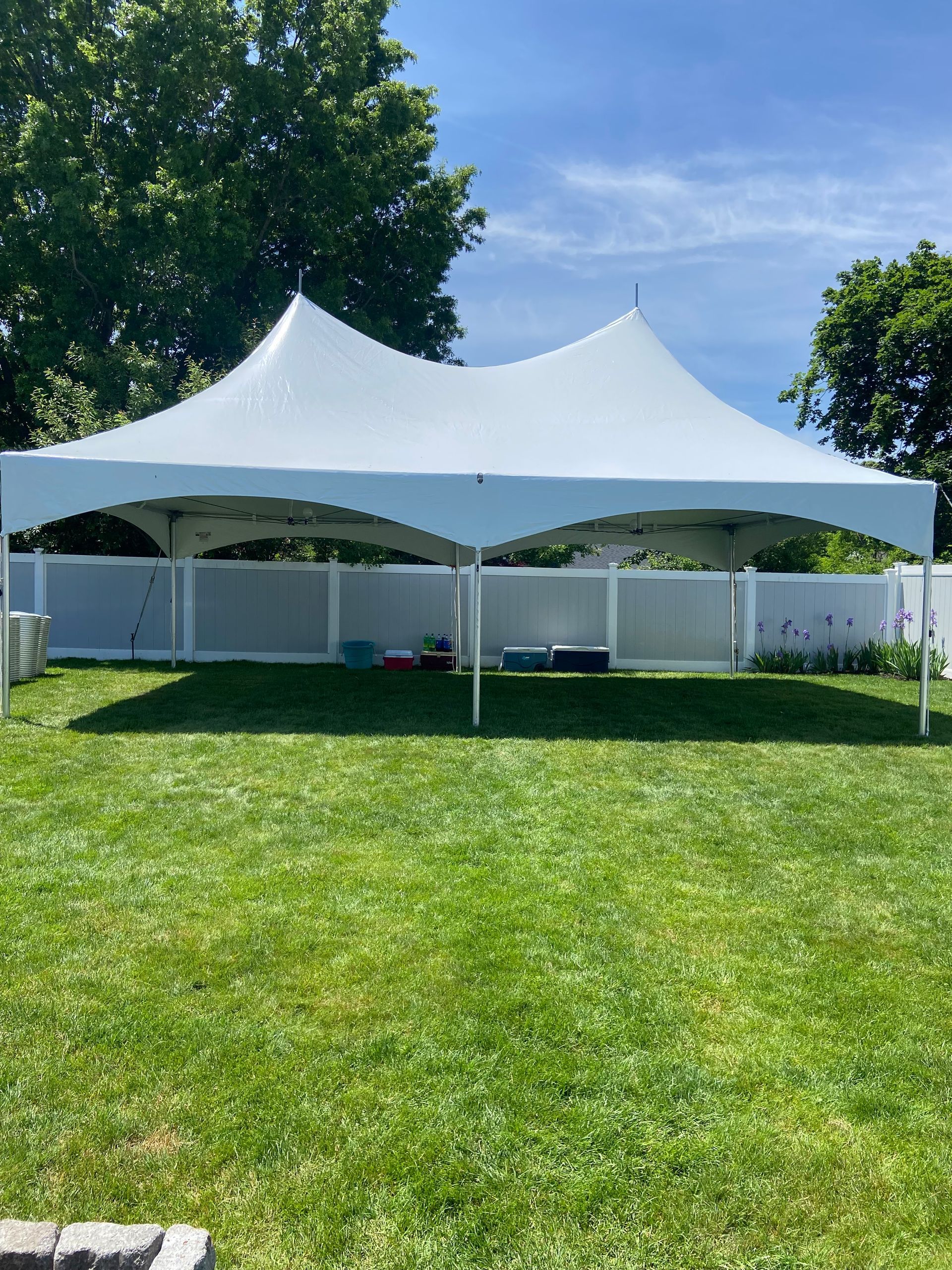 A large white tent is sitting in the middle of a lush green field.