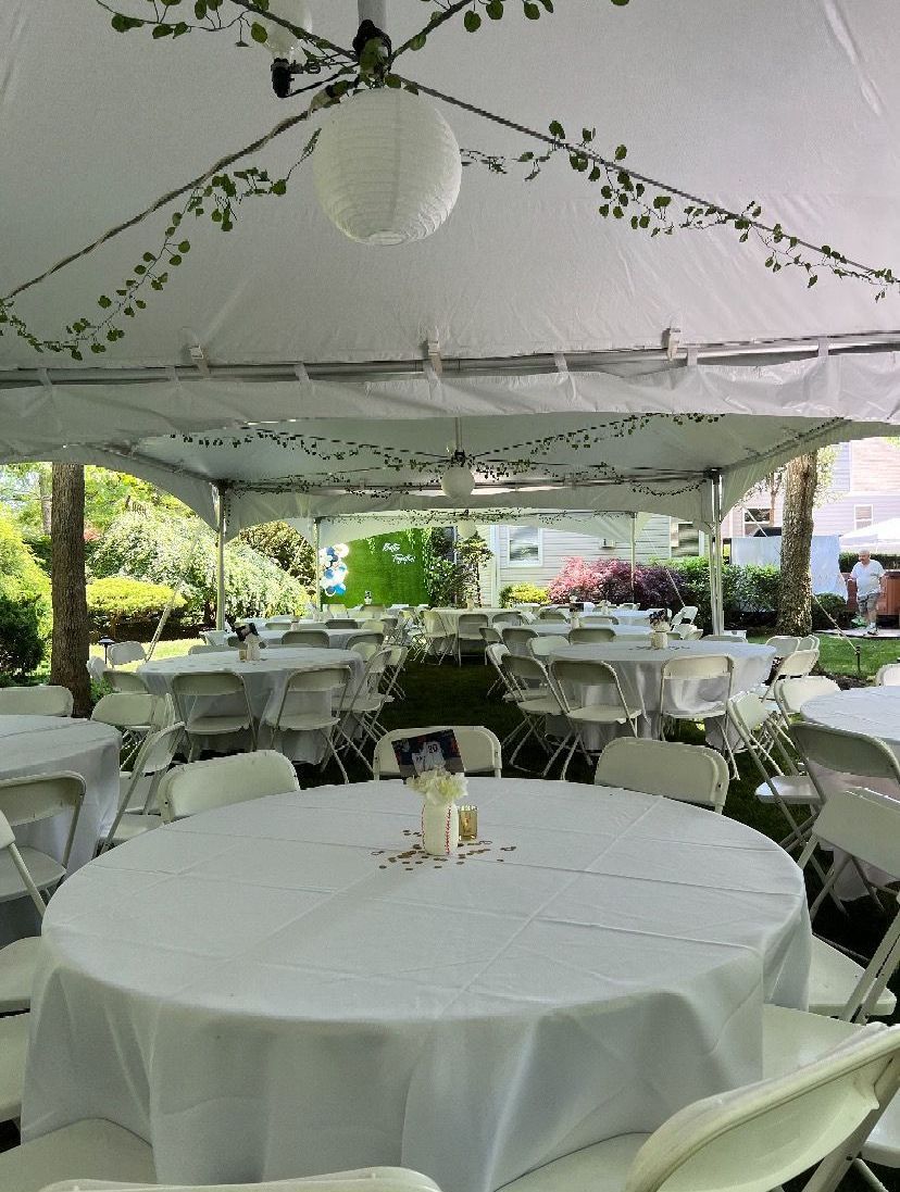 Tables and chairs are set up under a white tent