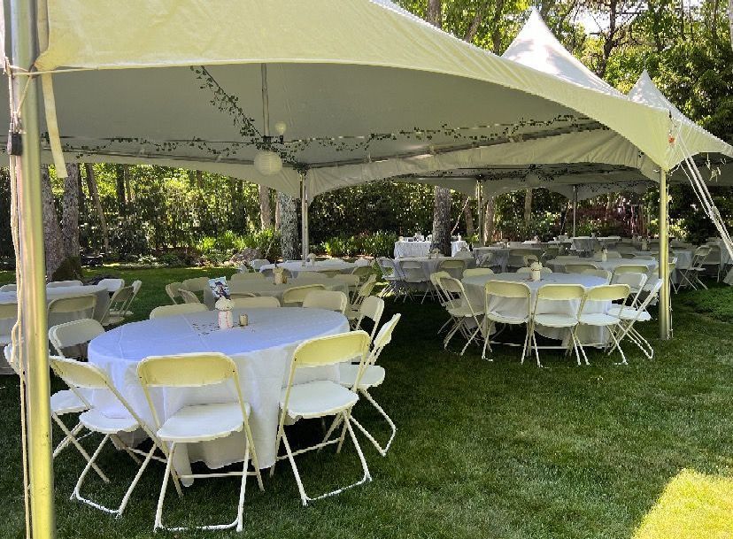 A large white tent with tables and chairs underneath it