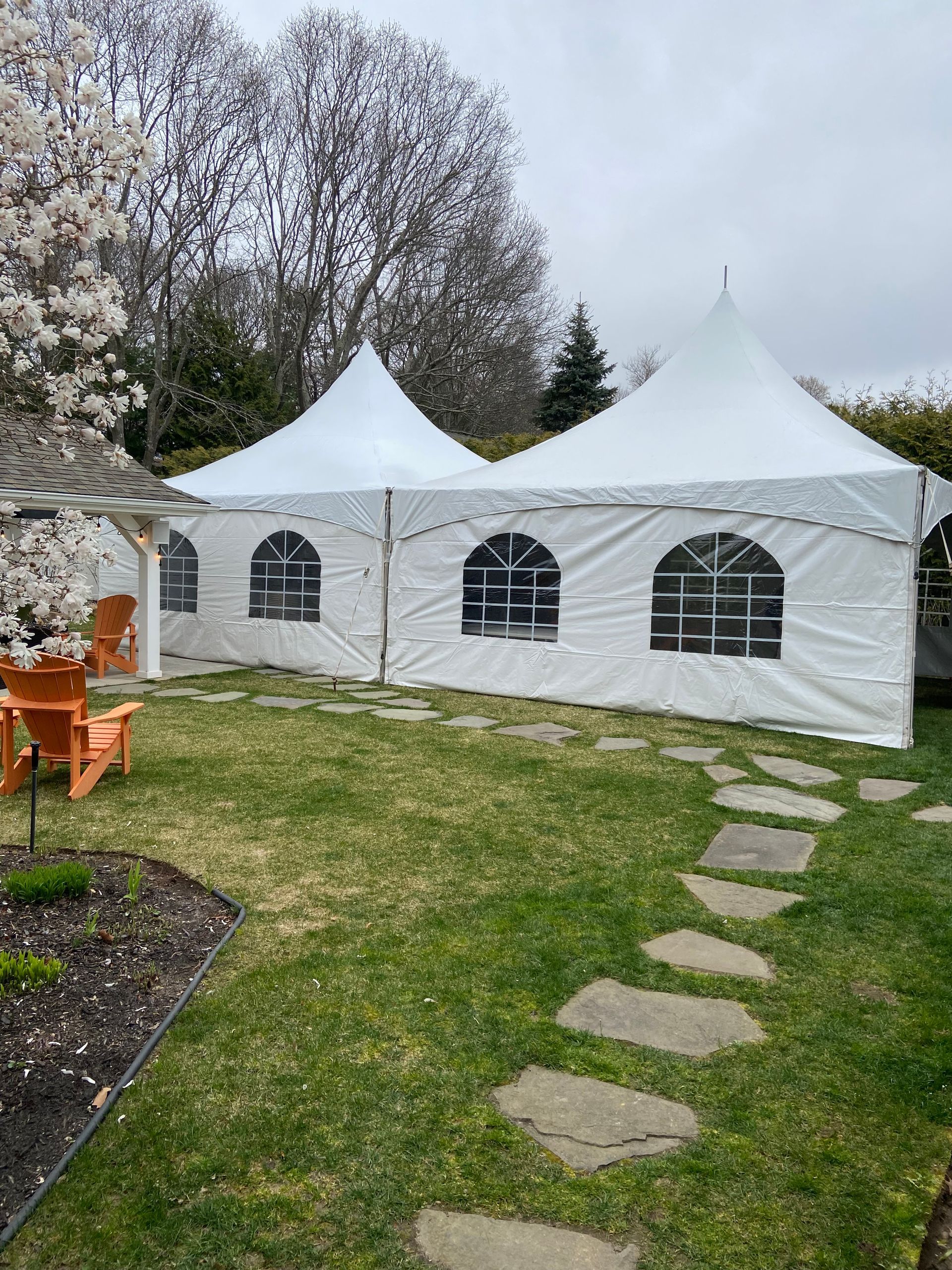 A large white tent is sitting in the middle of a lush green yard.
