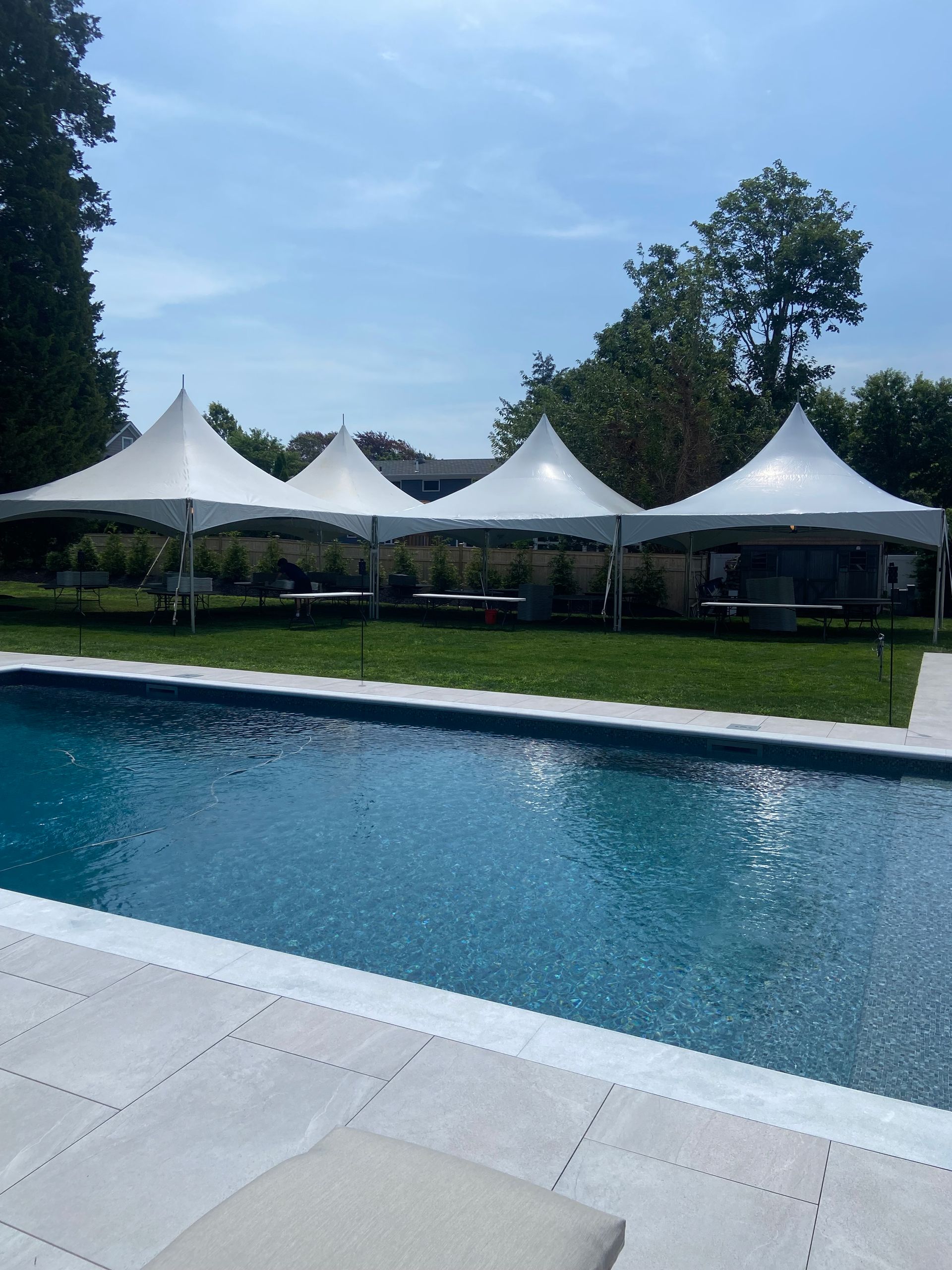 A swimming pool with white tents in the background