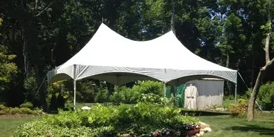 A white tent is sitting in the middle of a lush green field.