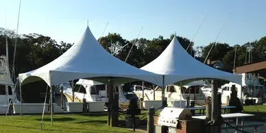 A group of white tents are sitting on top of a lush green field.