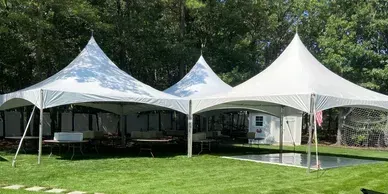 Three white tents are sitting on top of a lush green field.