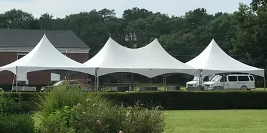 A row of white tents are sitting on top of a lush green field.