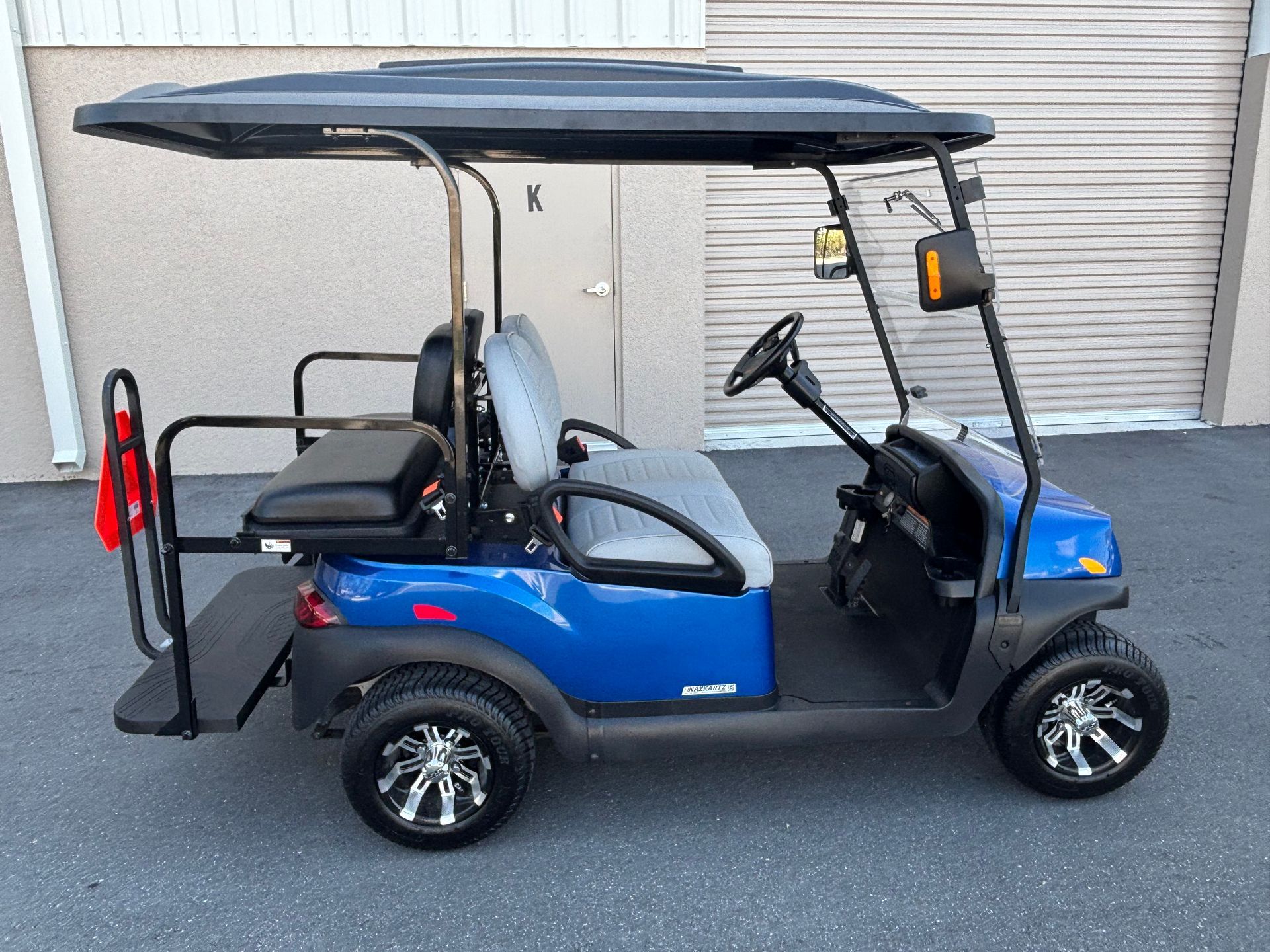 Blue golf cart with black roof parked outside.