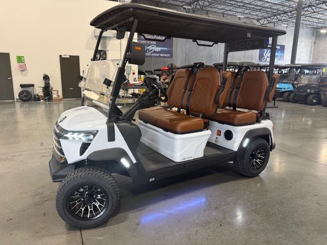 Green golf cart with black roof and wheels, parked in front of a banner.