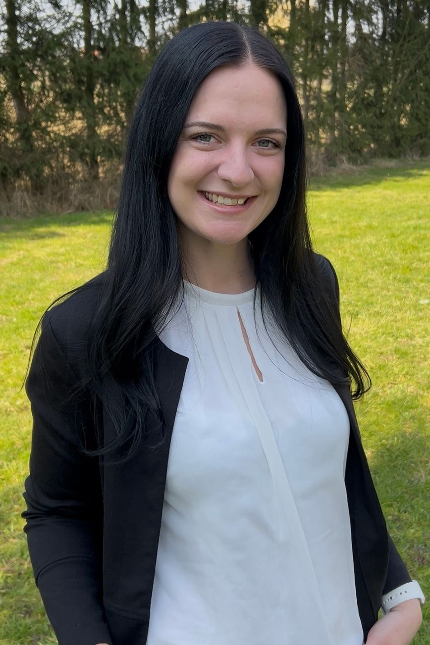 Eine Frau sitzt mit überkreuzten Beinen auf dem Boden und lächelt.