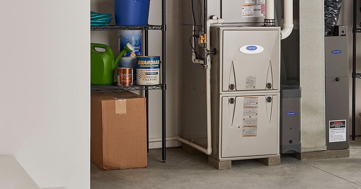 Furnace and utility area with shelving, cardboard box, and supplies.