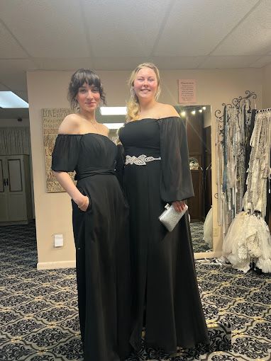 Two women in black dresses are standing next to each other in a room.
