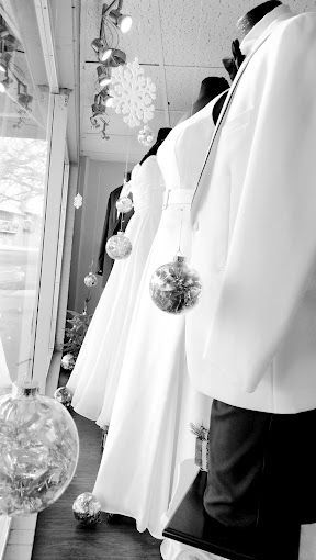 A black and white photo of a row of wedding dresses in a store window.