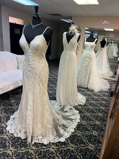 A room filled with lots of wedding dresses on mannequins.