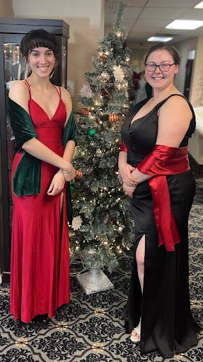 Two women are standing next to each other in front of a christmas tree.