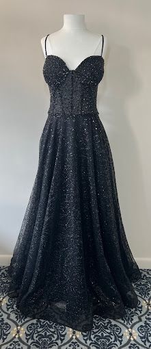 A black dress is on a mannequin on a tiled floor.