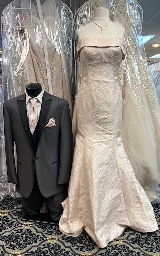 A bride and groom are standing next to each other in a wedding dress and tuxedo.